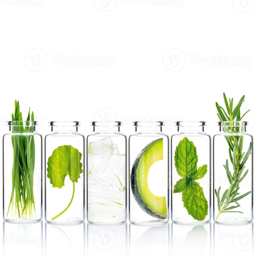 soins de la peau faits maison avec des ingrédients naturels herbe de blé, avocat, aloe vera, feuilles de menthe, centella asiatica et romarin dans des bouteilles en verre isoler sur fond blanc. photo