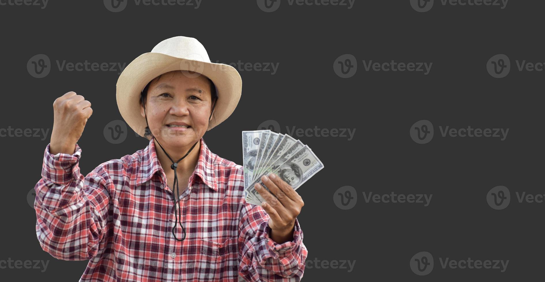 une femme asiatique âgée isolée nous tient des billets de banque en dollars à la main avec un beau sourire sur son visage joyeusement avec des chemins de détourage. photo