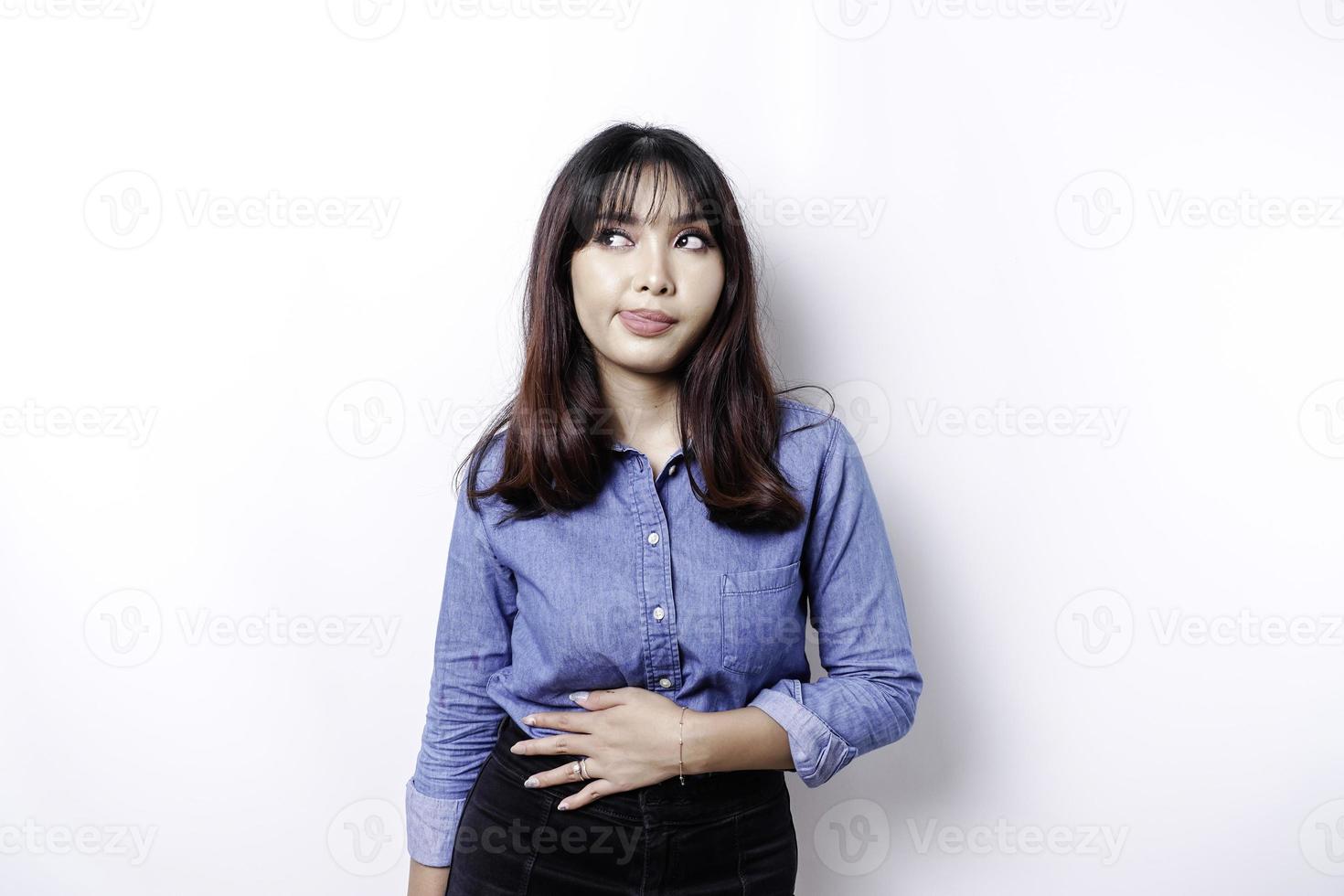 une femme asiatique a faim et touche son ventre tout en regardant de côté en pensant quoi manger photo