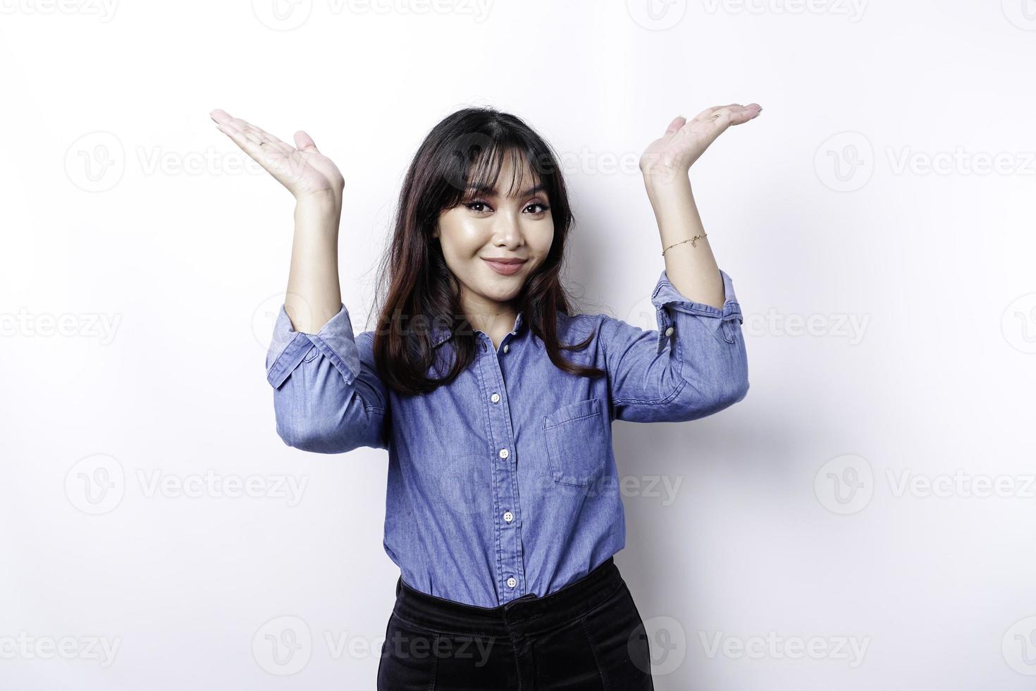 femme asiatique excitée portant une chemise bleue pointant vers l'espace de copie au-dessus d'elle, isolée par fond blanc photo