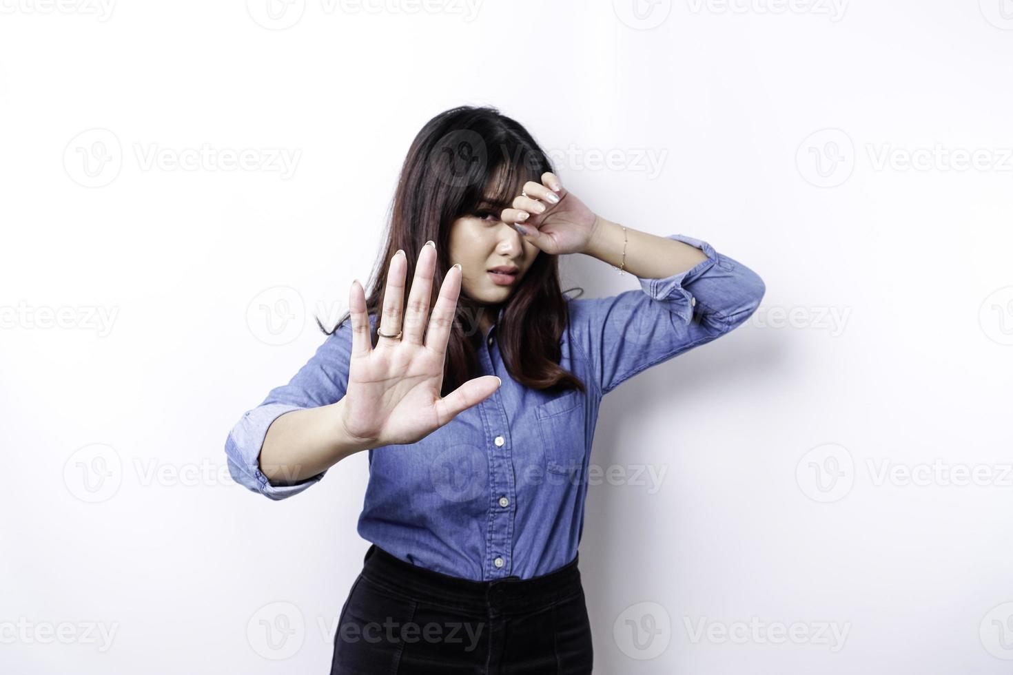 jeune femme asiatique isolée sur fond blanc, a l'air déprimée, le visage couvert de doigts effrayés et nerveux. photo