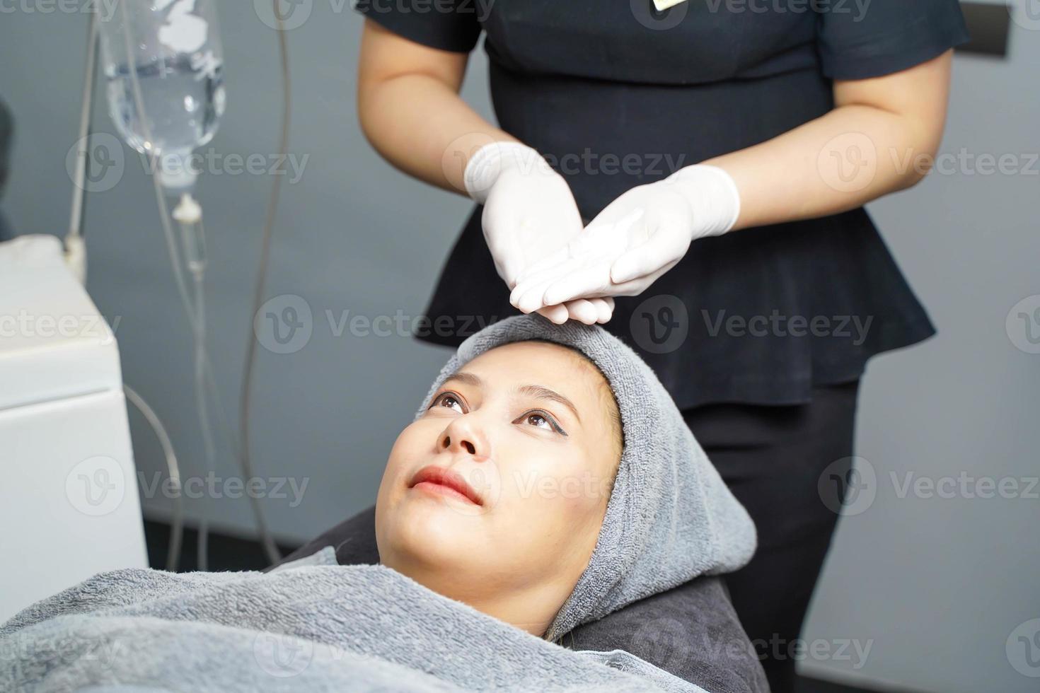 infirmière de beauté en gros plan montre de la crème de gommage du visage sur les mains avant de faire un massage du visage avec un gommage du visage bio sur le visage du client. photo