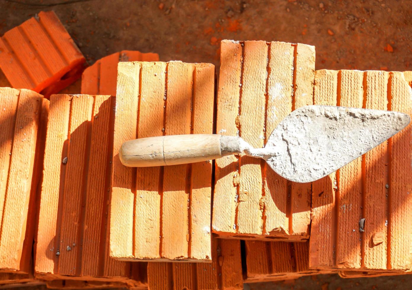 truelle utilisée posée sur un tas de briques sur le chantier de construction. photo