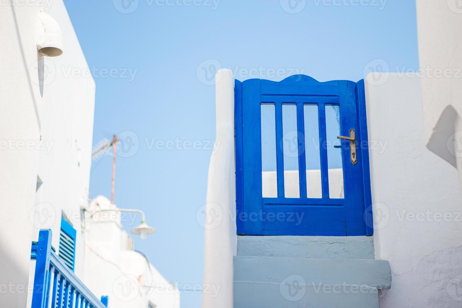 maisons traditionnelles avec porte bleue et escaliers blancs dans les rues étroites de mykonos, grèce. photo