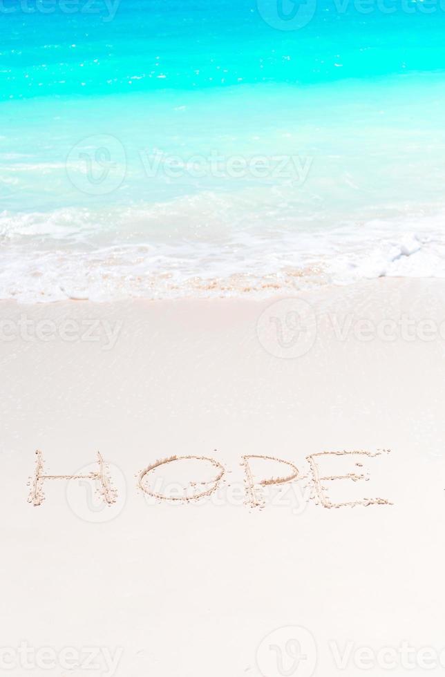écrit à la main sur une plage de sable avec une douce vague océanique sur fond photo