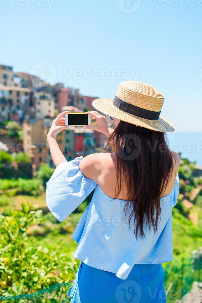 jeune femme prend une photo de la belle vue sur le vieux village de cinque terre, ligurie, italie. vacances italiennes européennes.