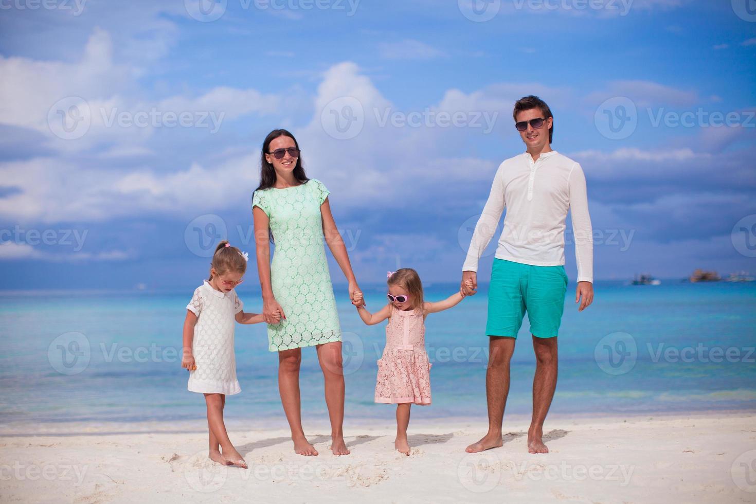 mode famille de quatre personnes marchant au bord de la mer et profitant de vacances à la plage photo