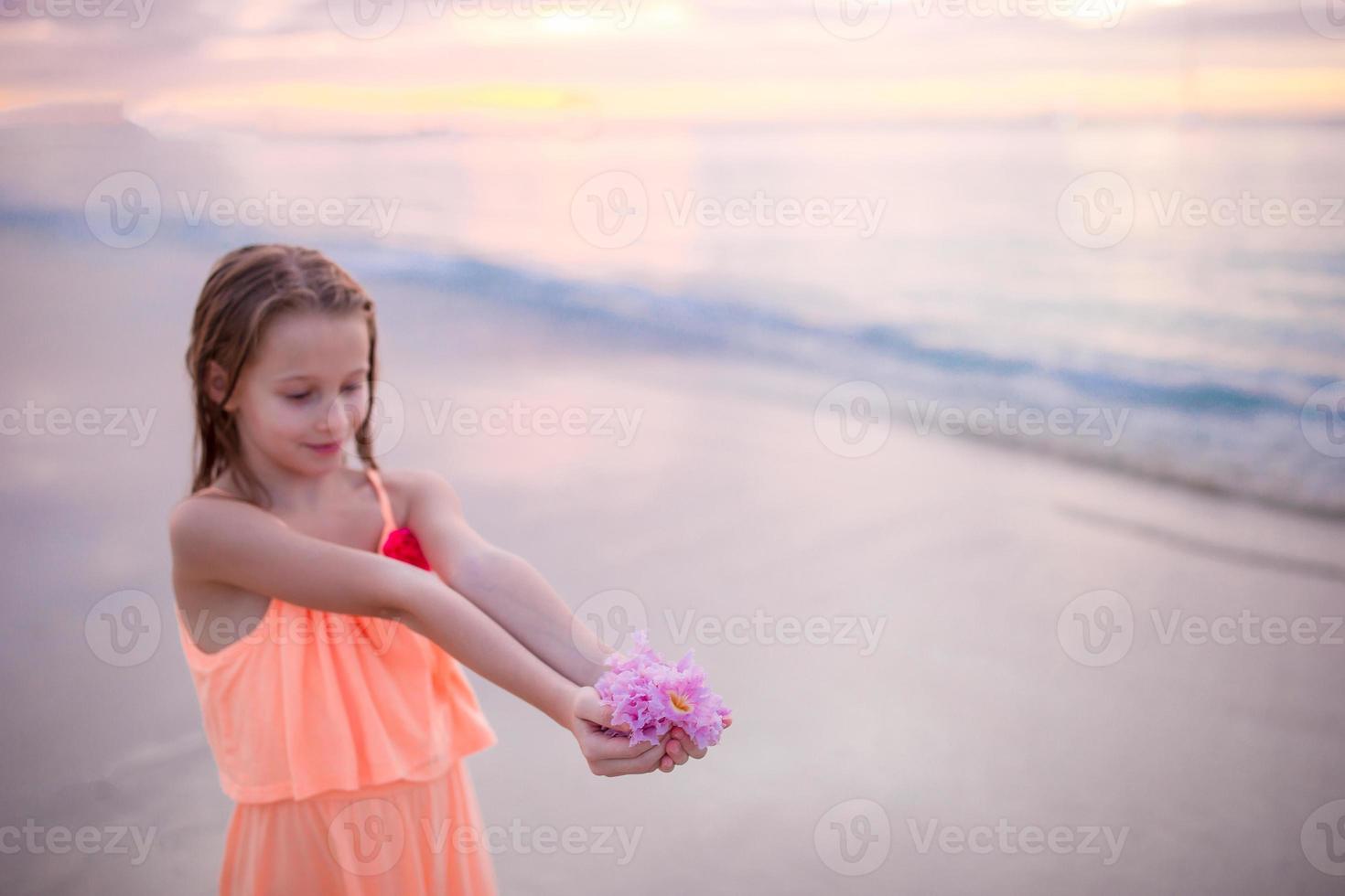 belle petite fille en robe à la plage s'amusant. fille drôle profite des vacances d'été. photo