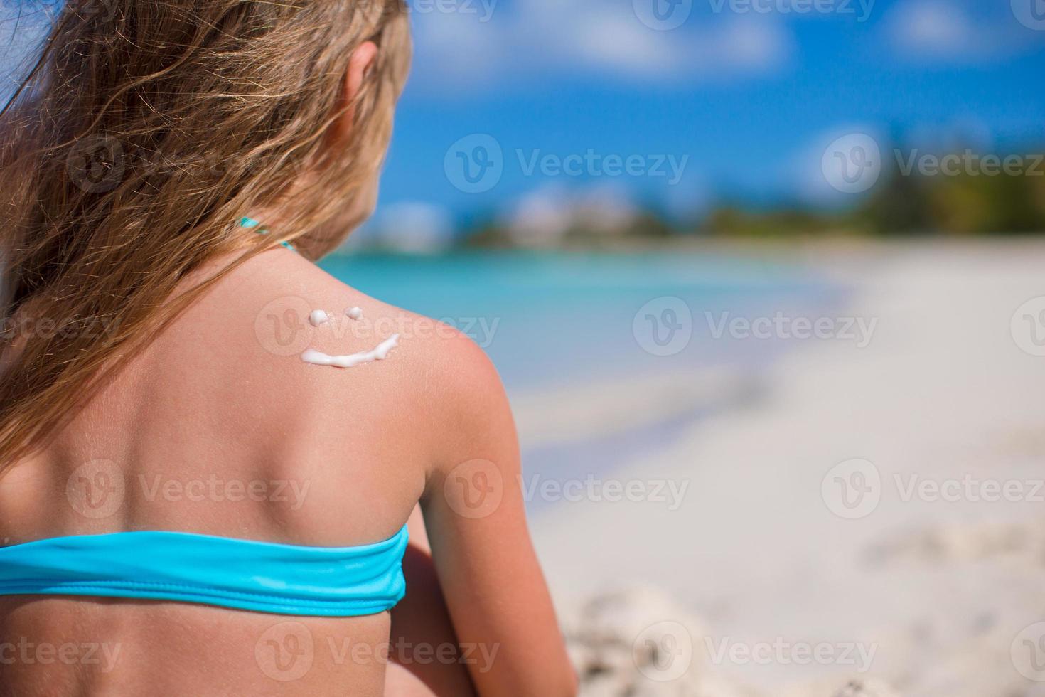 sourire en gros plan peint par la crème solaire sur l'épaule de l'enfant photo