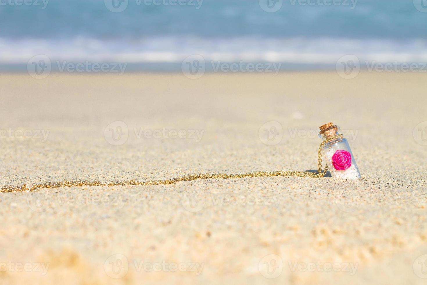 petite bouteille souvenir sur fond de sable blanc la mer turquoise photo