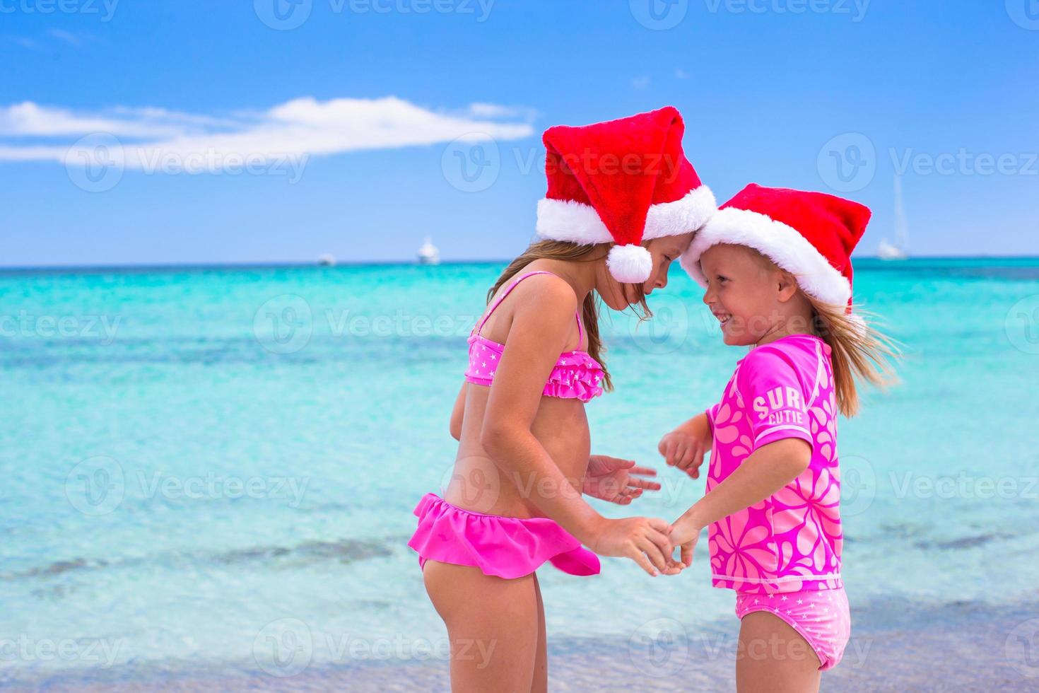 petites filles adorables en chapeaux de père noël pendant les vacances à la plage photo