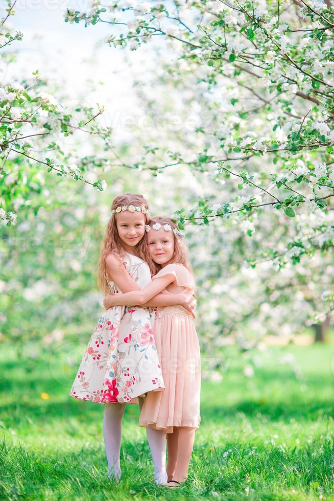 adorables petites filles dans un jardin de cerisiers en fleurs le jour du printemps photo