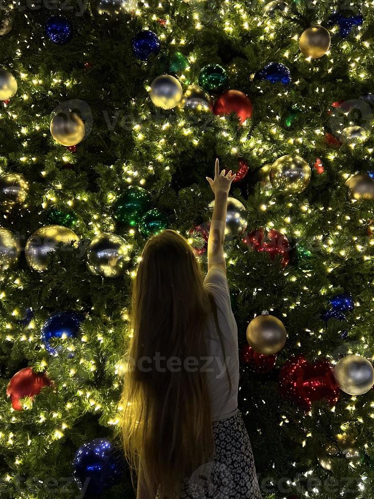 jeune fille sur le fond de l'arbre de noël à miami. beau sapin de noël dans le quartier populaire à la veille de noël et lumières photo