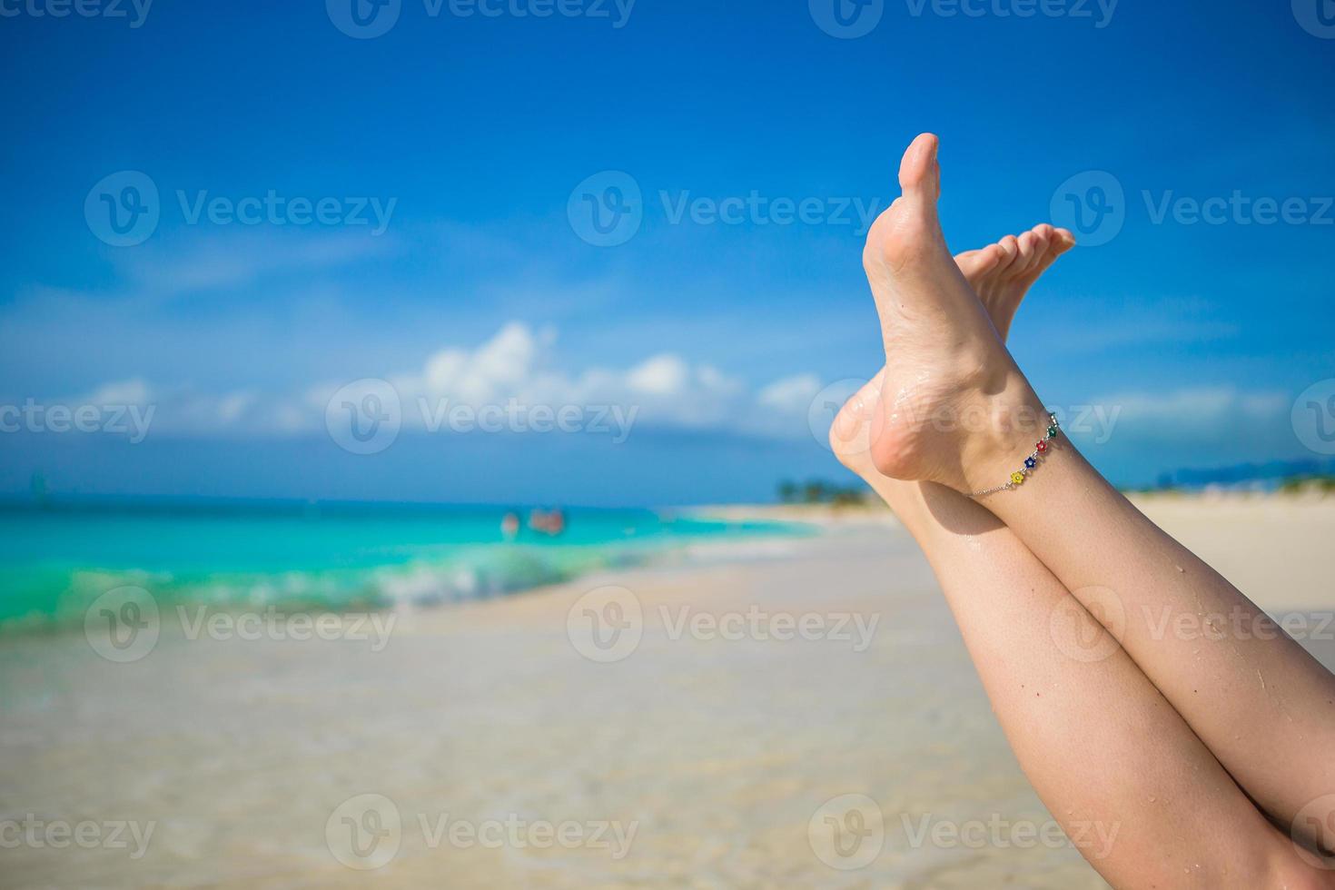 gros plan de pieds féminins sur une plage de sable blanc photo