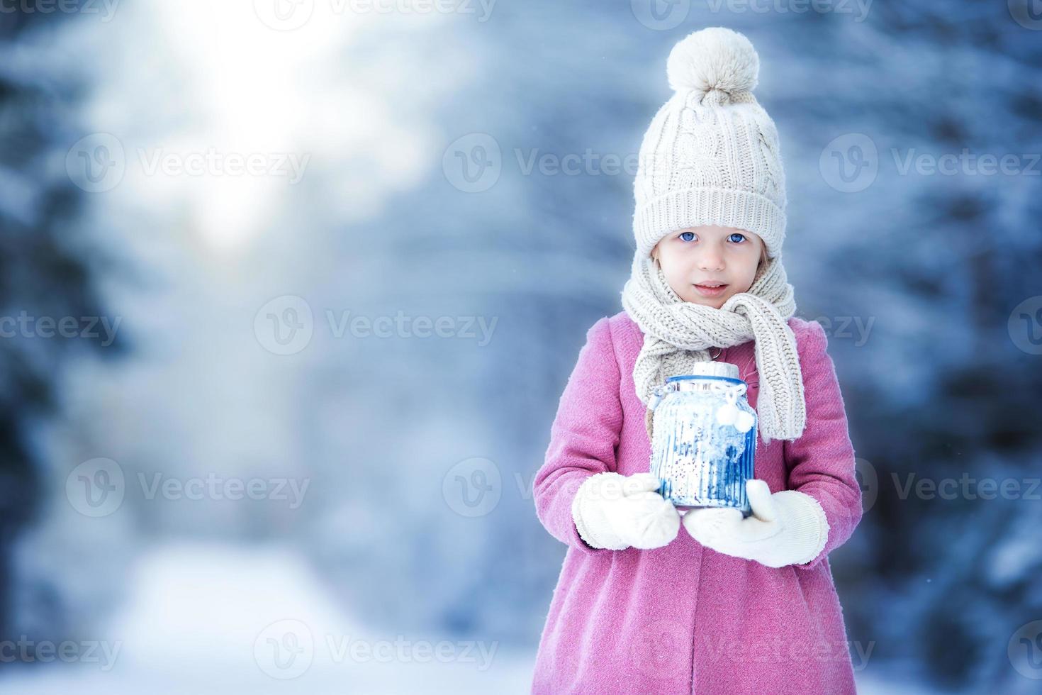 adorable petite fille avec lampe de poche et bougie en hiver à noël à l'extérieur photo