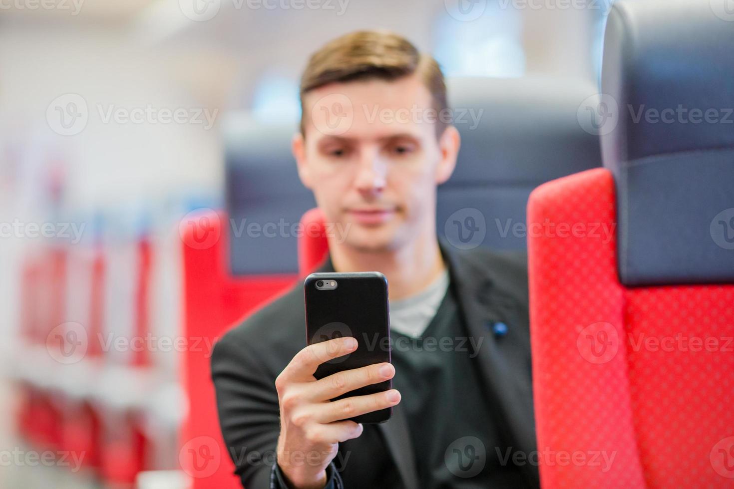 jeune homme voyageant en train. touriste écrivant un message sur son téléphone portable lors d'un voyage en train express photo