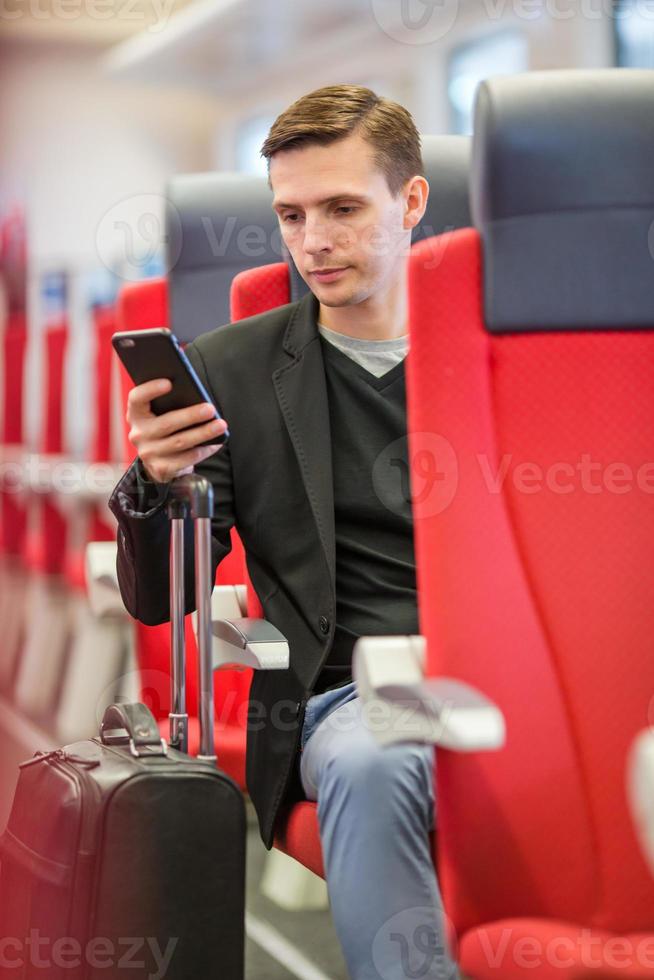 jeune homme voyageant en train. touriste écrivant un message sur son téléphone portable lors d'un voyage en train express photo