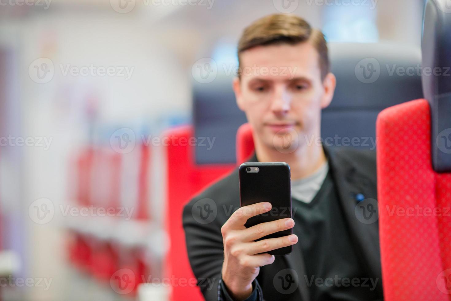 jeune homme caucasien voyageant en train. touriste écrivant un message sur son téléphone portable lors d'un voyage en train express photo