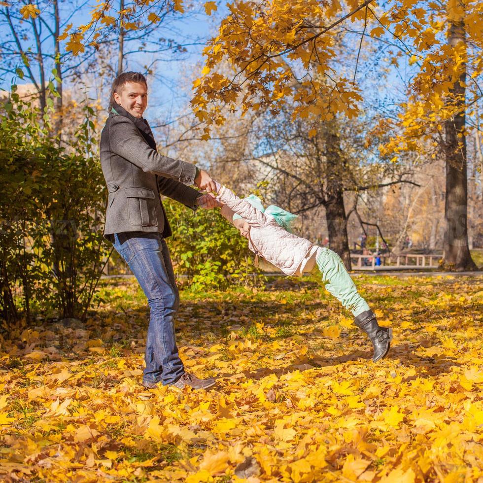 jolie petite fille avec papa heureux s'amusant dans le parc d'automne par une journée ensoleillée photo