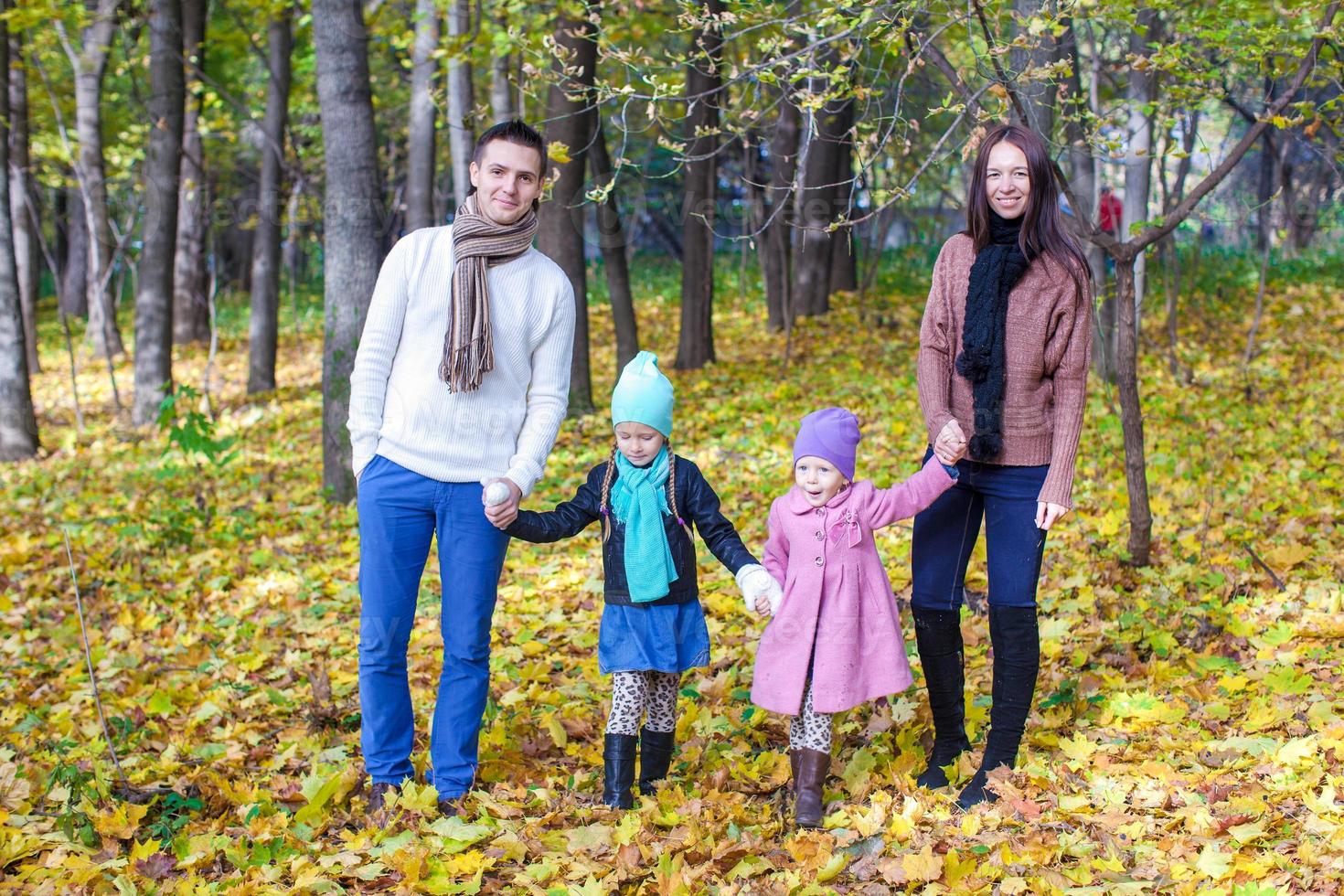 famille de quatre personnes se promène dans le parc d'automne par une chaude journée ensoleillée photo