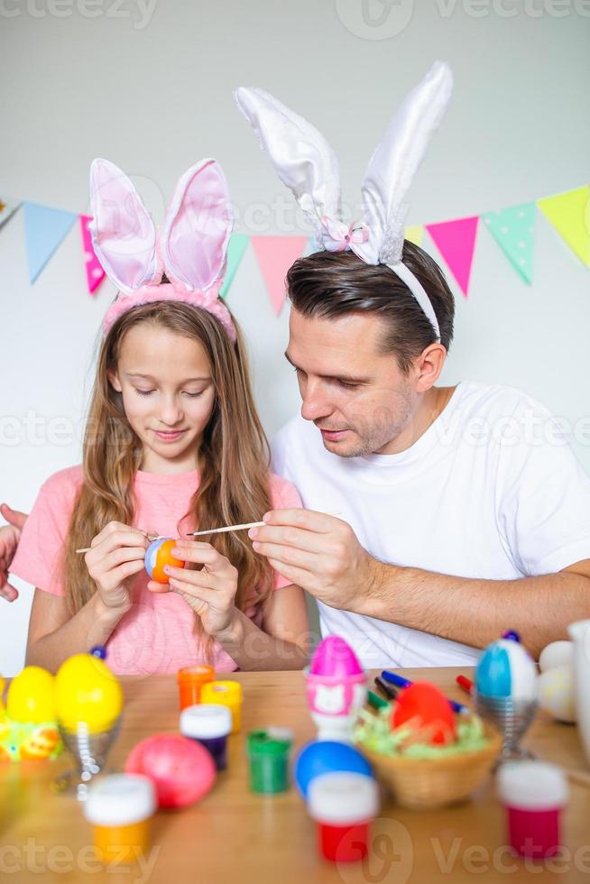 père et sa petite fille peignant des œufs. famille heureuse se préparant pour pâques. photo