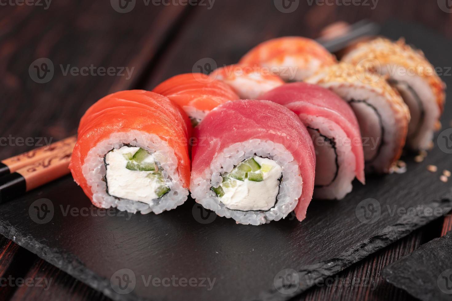 petits pains sertis de poisson saumon et crevettes et thon sushi d'anguille maguro avec gros plan de baguettes - concept de cuisine asiatique et de cuisine japonaise photo