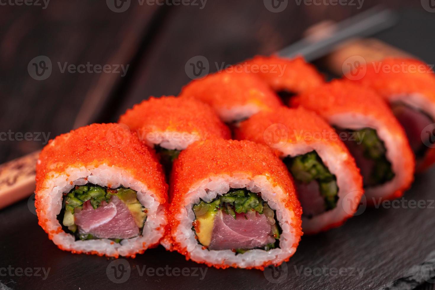 rouleau de sushi californien au thon, concombre à l'avocat et caviar de tobiko servi sur un tableau noir en gros plan - cuisine japonaise photo