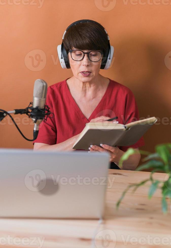 femme faisant un enregistrement de podcast pour son émission en ligne. Jolie femme d'affaires à l'aide d'écouteurs devant le microphone pour une émission de radio photo