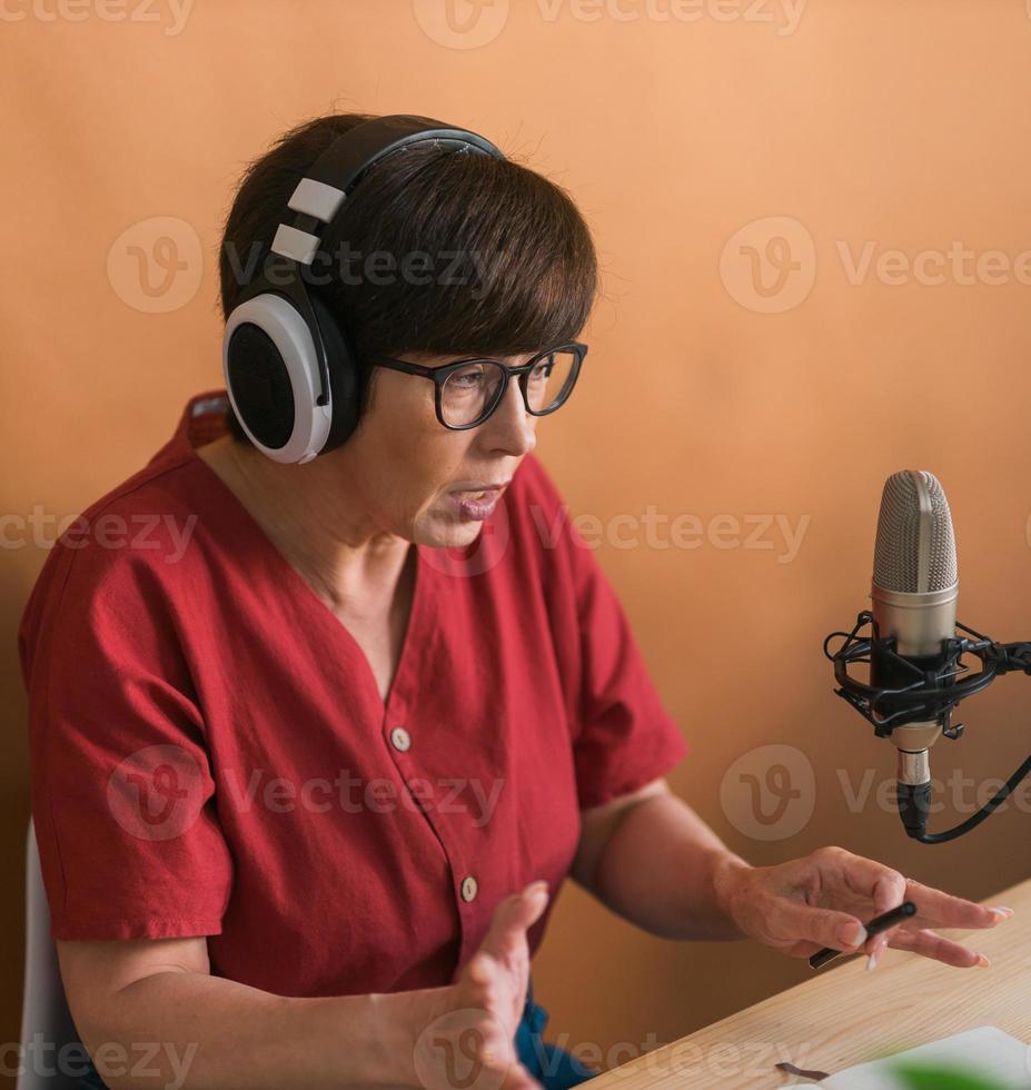 portrait d'une femme mûre portant des écouteurs et parlant à la station de radio en ligne - concept de podcast et de diffusion photo