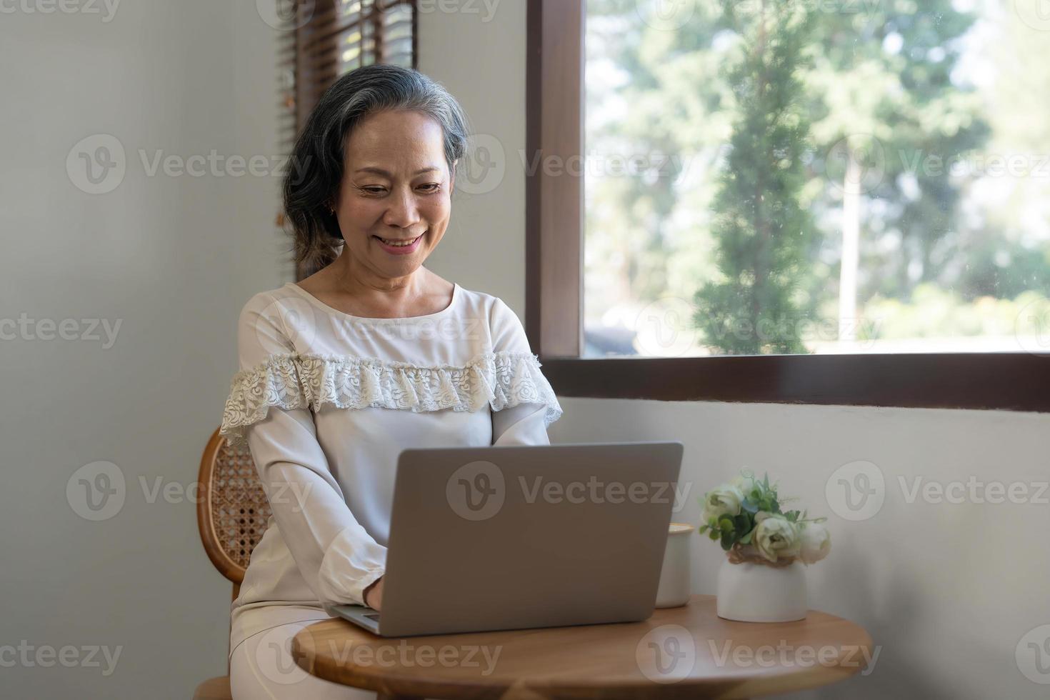 portrait, femme d'affaires asiatique âgée professionnelle et réussie travaillant à domicile, sirotant un café le matin tout en utilisant un ordinateur portable. photo