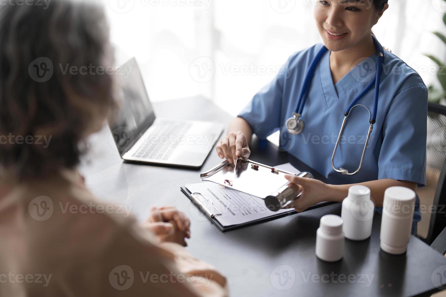 une patiente âgée âgée asiatique consulte une infirmière médecin dans une maison de soins infirmiers. soignant thérapeute pharmacien fille tenir une bouteille de pilules de médecine, expliquer la prescription à un homme handicapé plus âgé photo