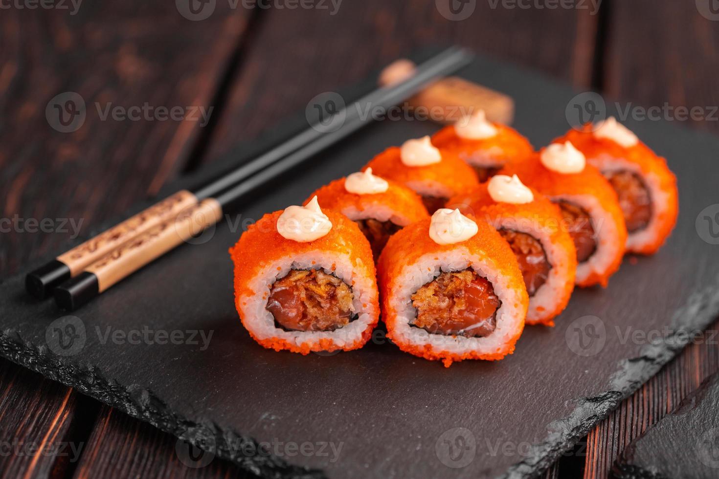 rouleau de sushi au thon, oignon dans la pâte et caviar tobiko servi sur tableau noir en gros plan - cuisine japonaise photo