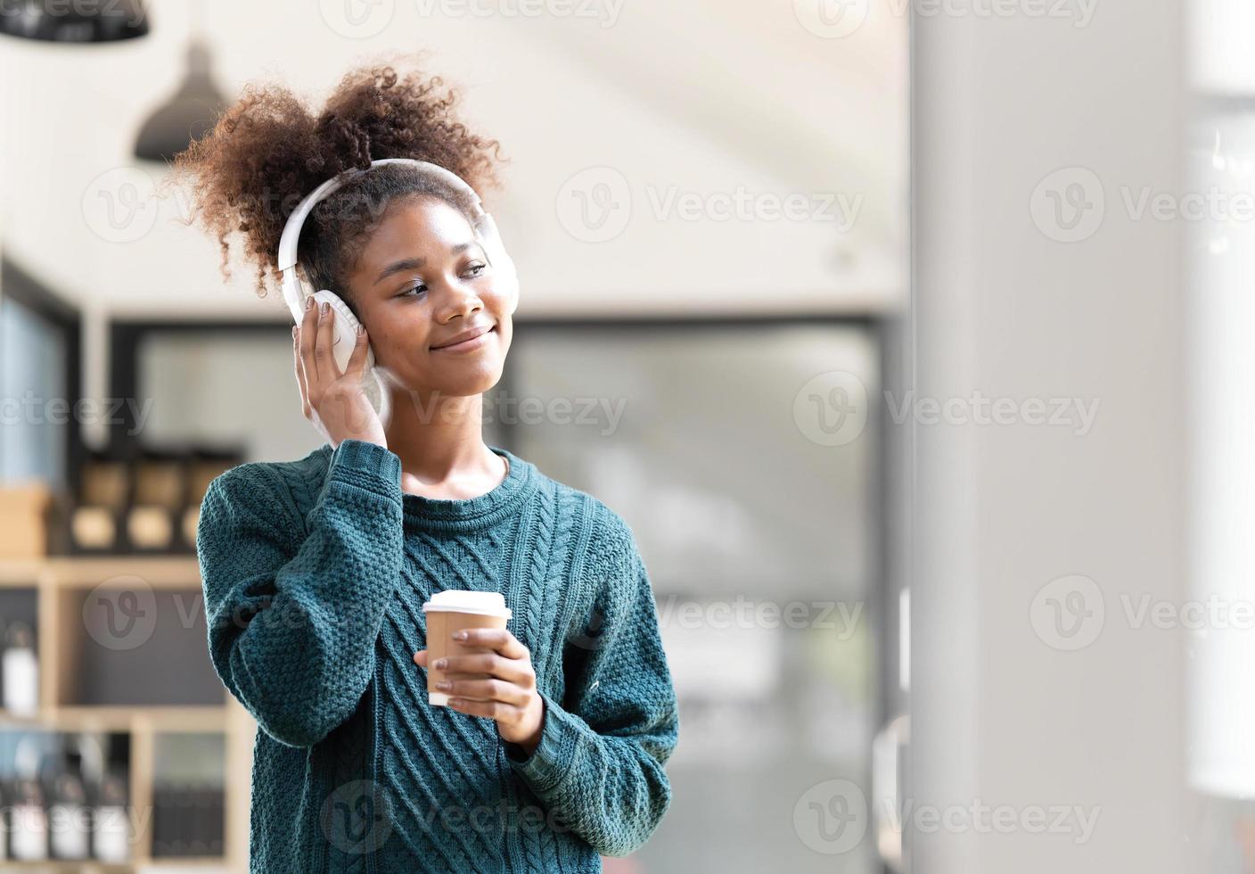 portrait d'une jeune femme noire souriante écoutant de la musique avec un casque et une tablette numérique photo