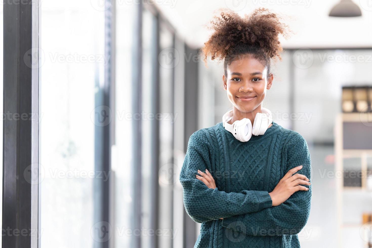 portrait d'une jeune femme noire souriante écoutant de la musique avec un casque et une tablette numérique photo