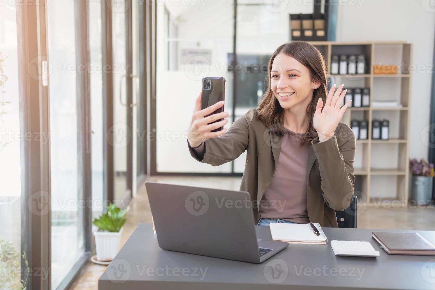 marketing, finance, comptabilité, planification, femme d'affaires de nationalité bi parle avec un client représentant un distributeur d'entreprise à l'aide d'un smartphone avec un stylo pour ordinateur portable et un bloc-notes sur le bureau. photo