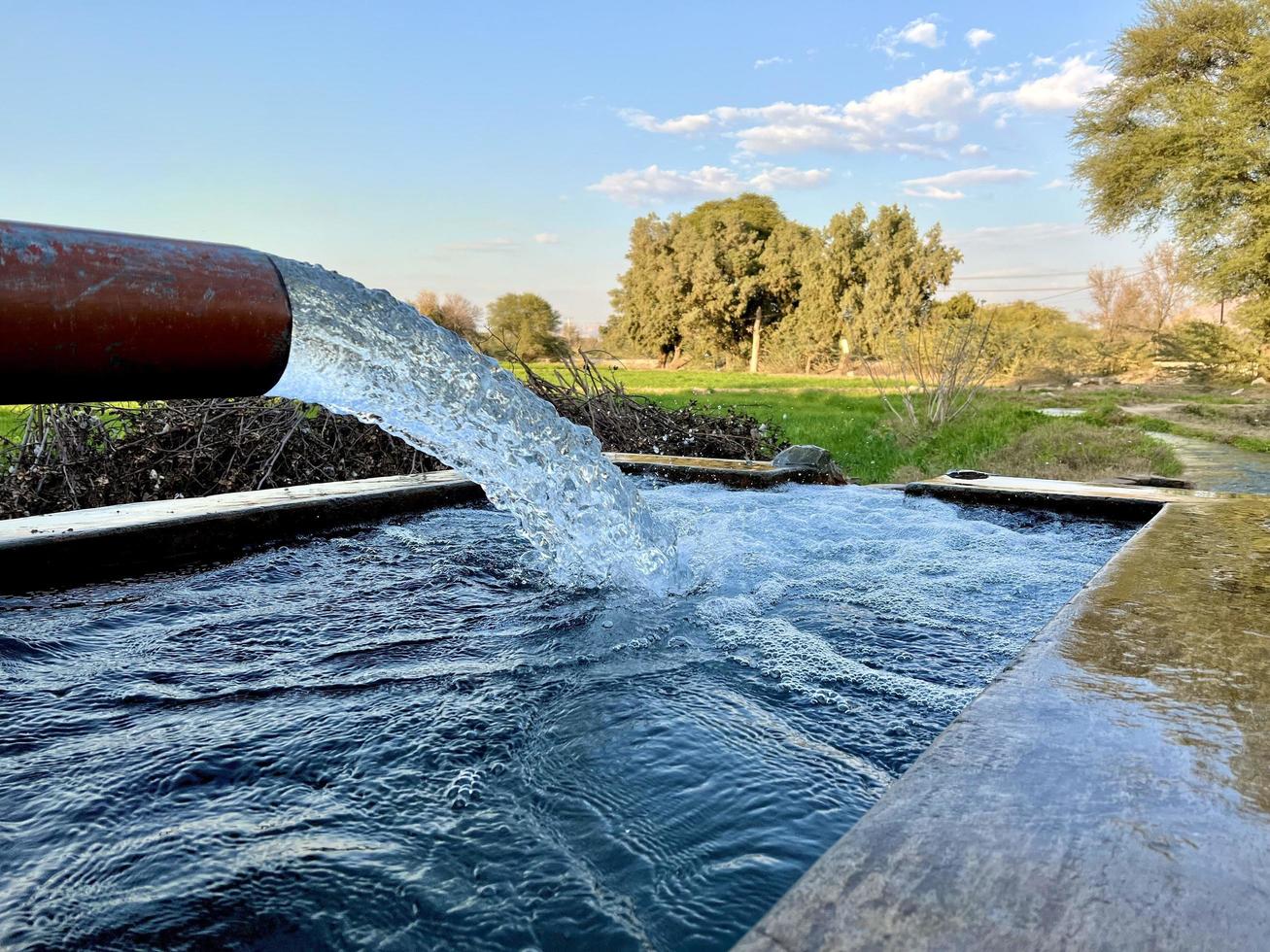 débit d'eau d'irrigation du tuyau au canal pour les champs agricoles photo