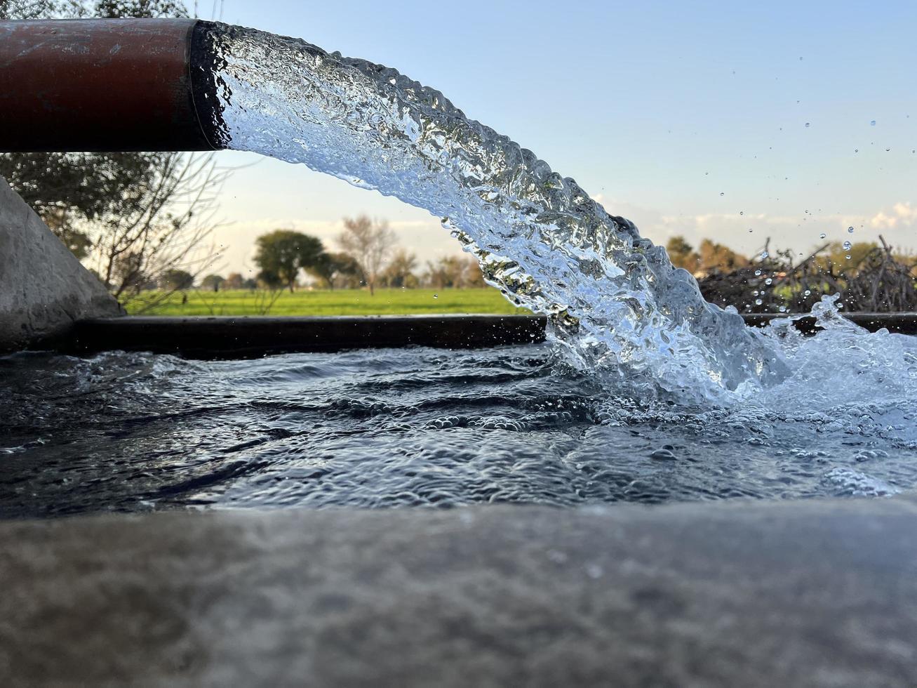 débit d'eau d'irrigation du tuyau au canal pour les champs agricoles photo