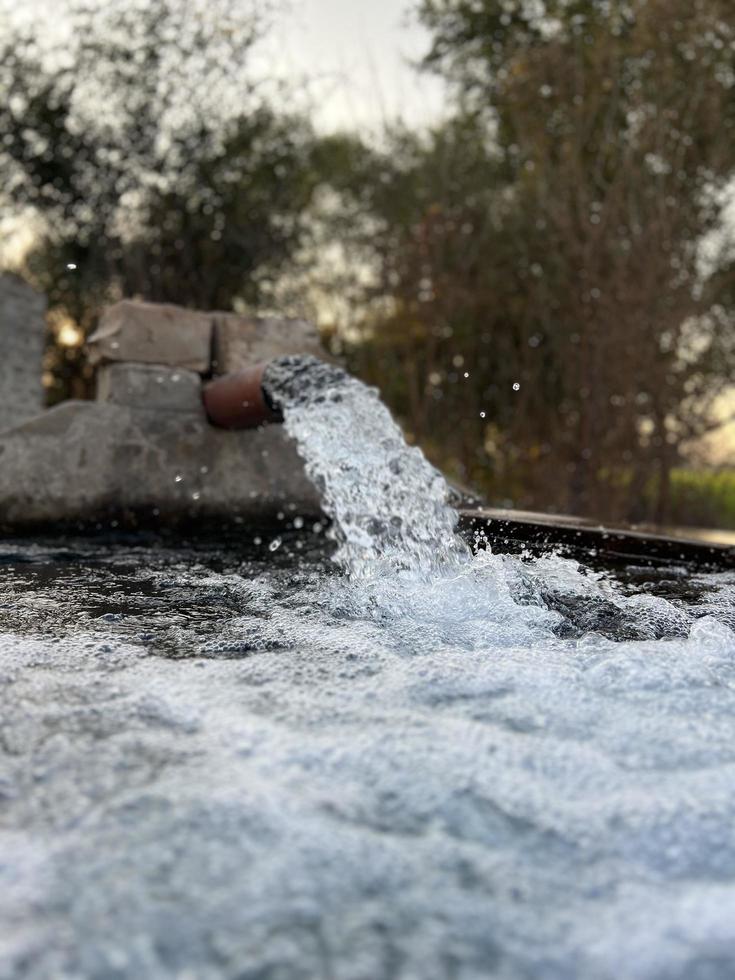 débit d'eau d'irrigation du tuyau au canal pour les champs agricoles photo