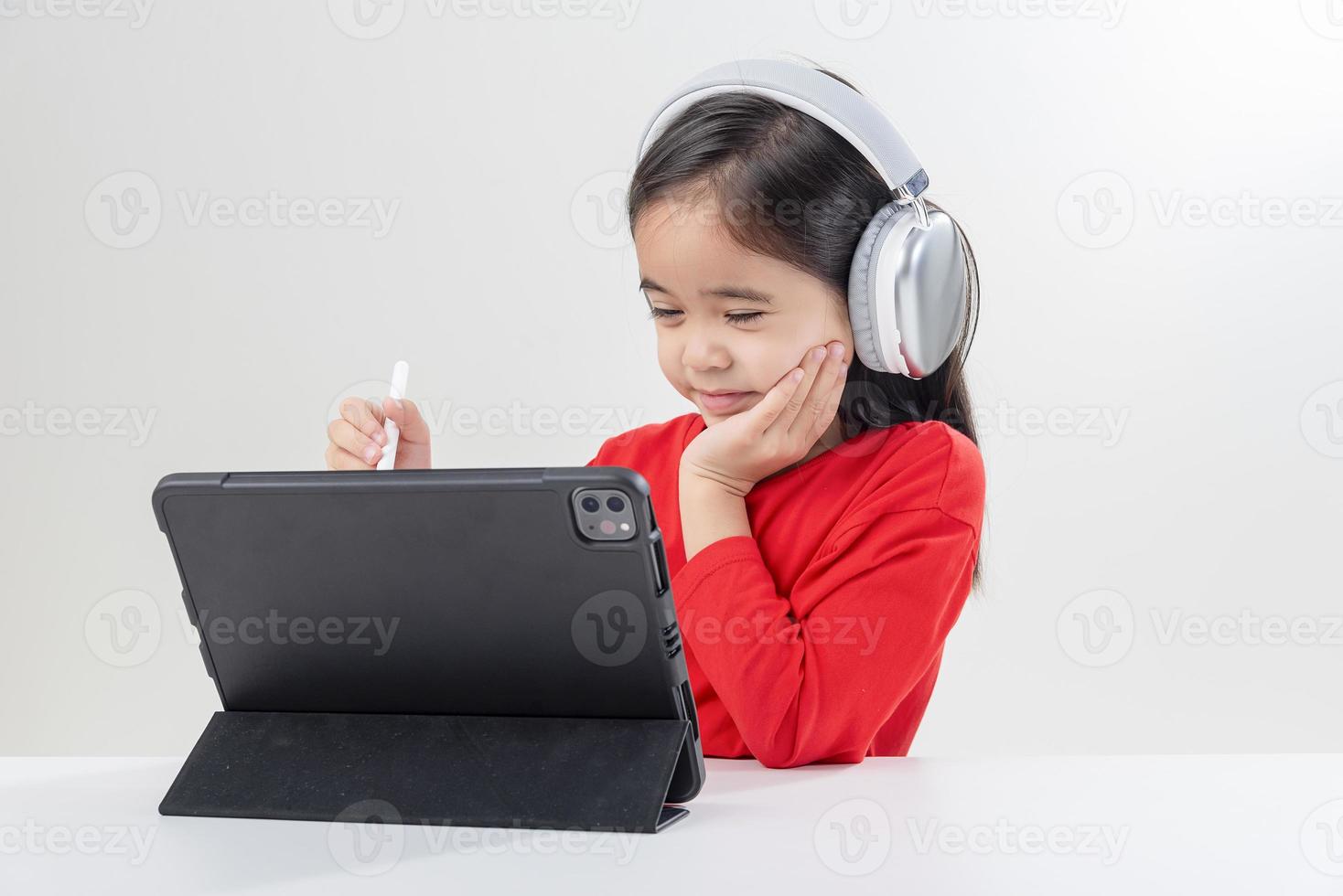 petite fille asie mignonne mettre des écouteurs avoir une classe distante d'appel vidéo avec un enseignant utilisant un ordinateur portable, étudier en ligne sur ordinateur, concept d'enseignement à domicile photo