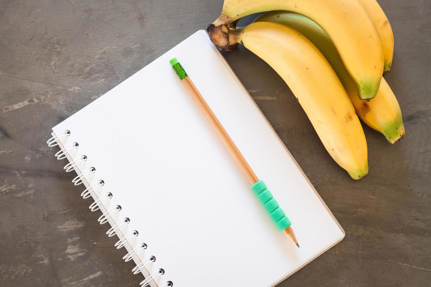 cahier avec un crayon vert et des bananes photo