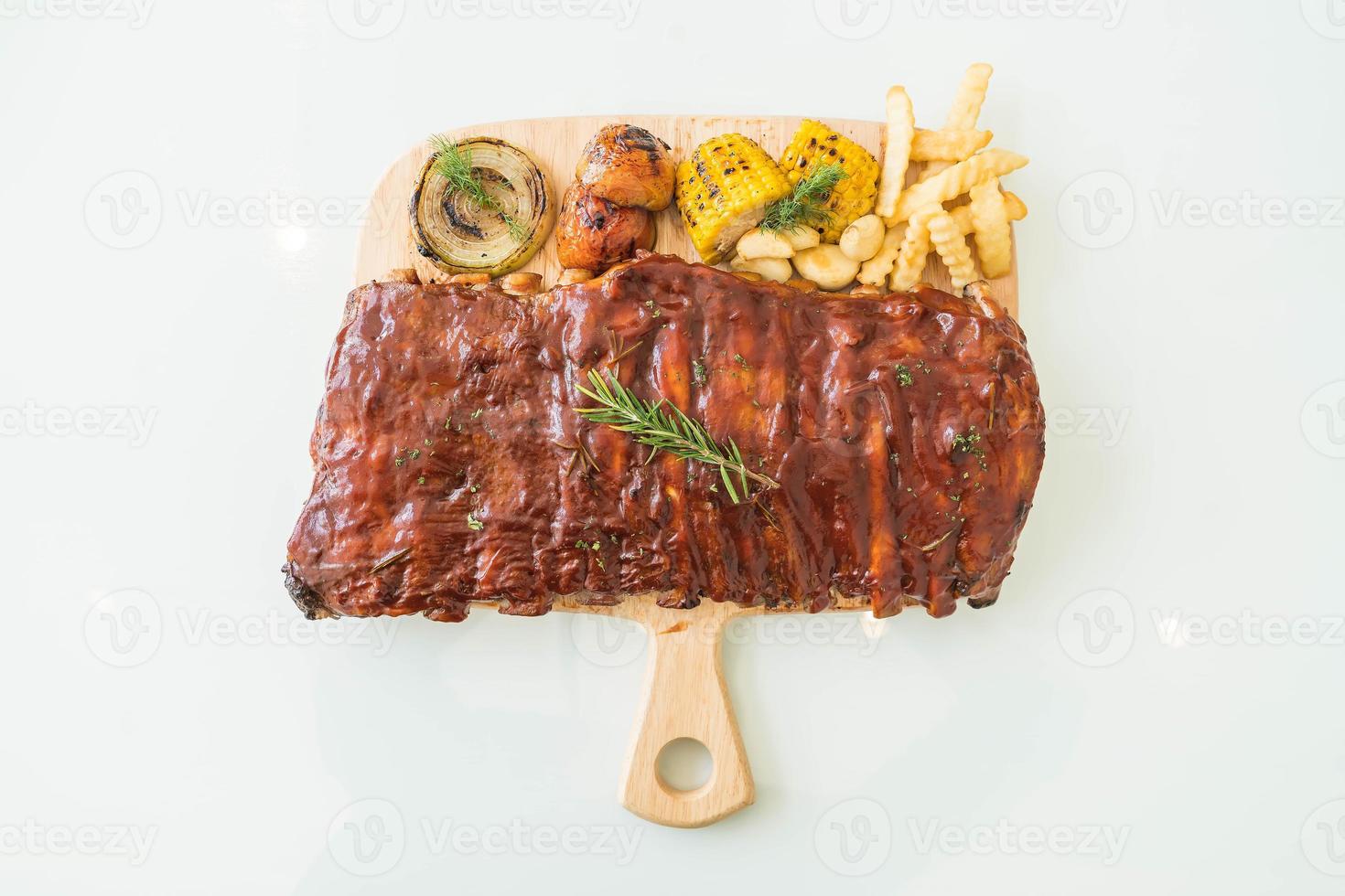 Côtes levées grillées aux légumes et frites sur une planche à découper en bois photo