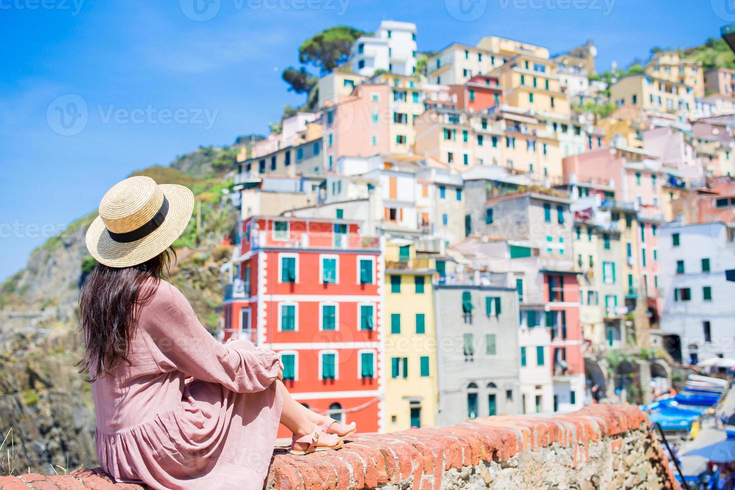 jeune femme avec une vue magnifique sur le vieux village de riomaggiore, cinque terre, ligurie, italie. vacances italiennes européennes. photo