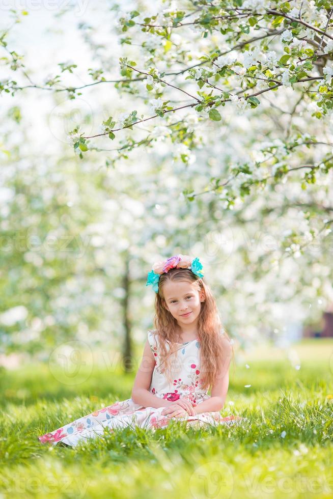 adorable petite fille dans un jardin de pommiers en fleurs le beau jour du printemps photo