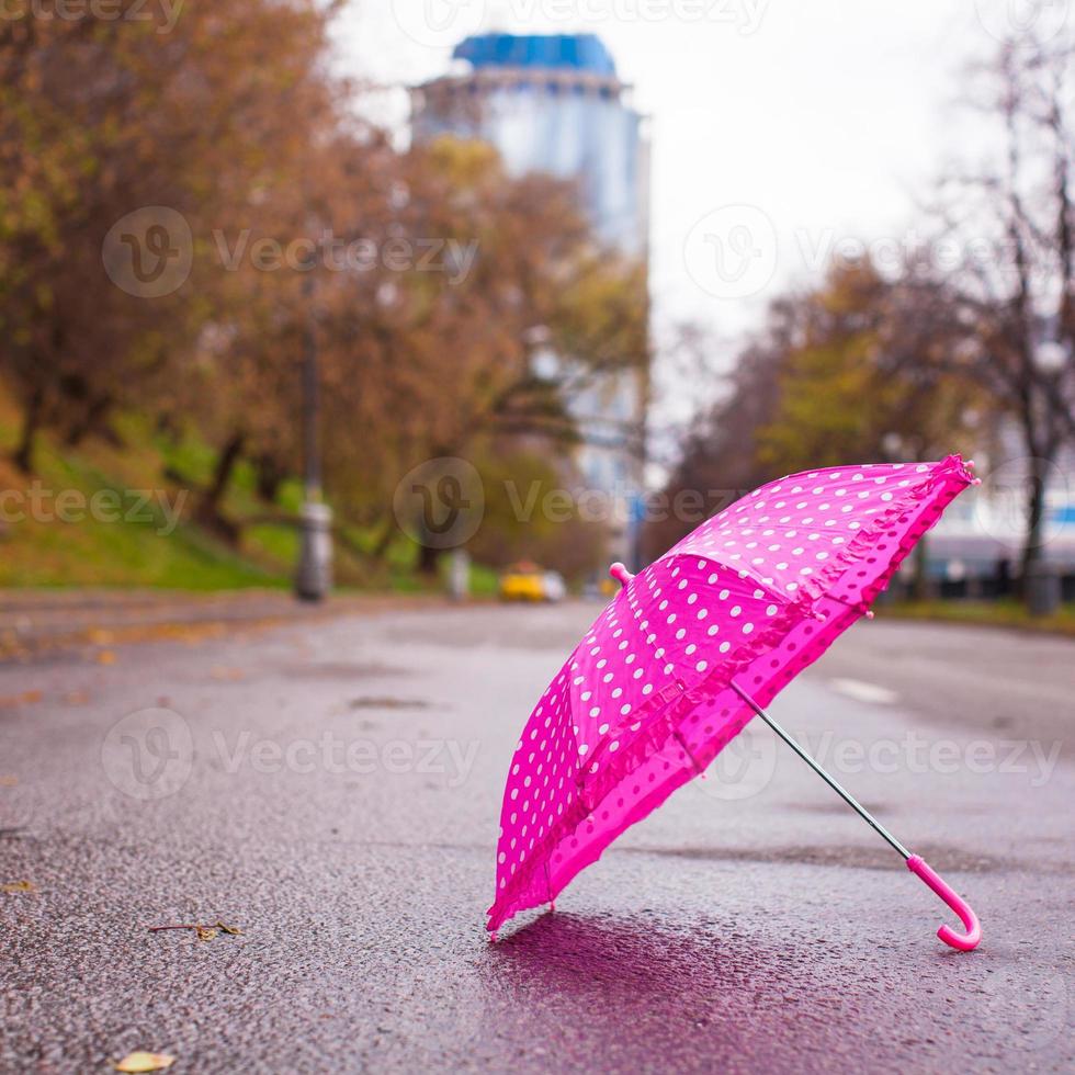 parapluie rose pour enfants sur l'asphalte mouillé à l'extérieur photo