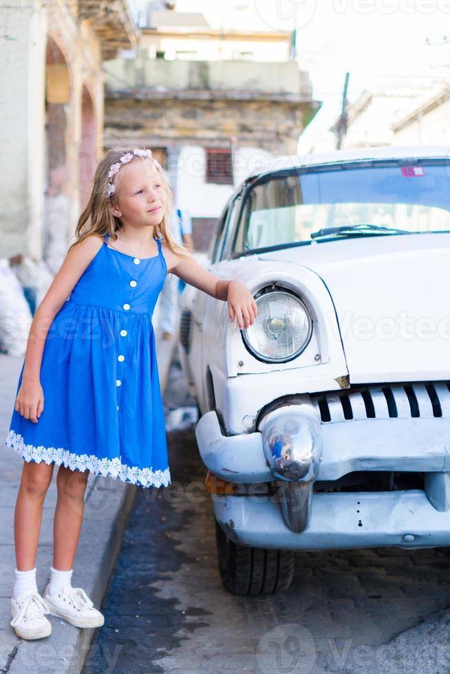 adorable petite fille dans un quartier populaire de la vieille havane, cuba. portrait d'enfant arrière-plan voiture américaine classique vintage photo