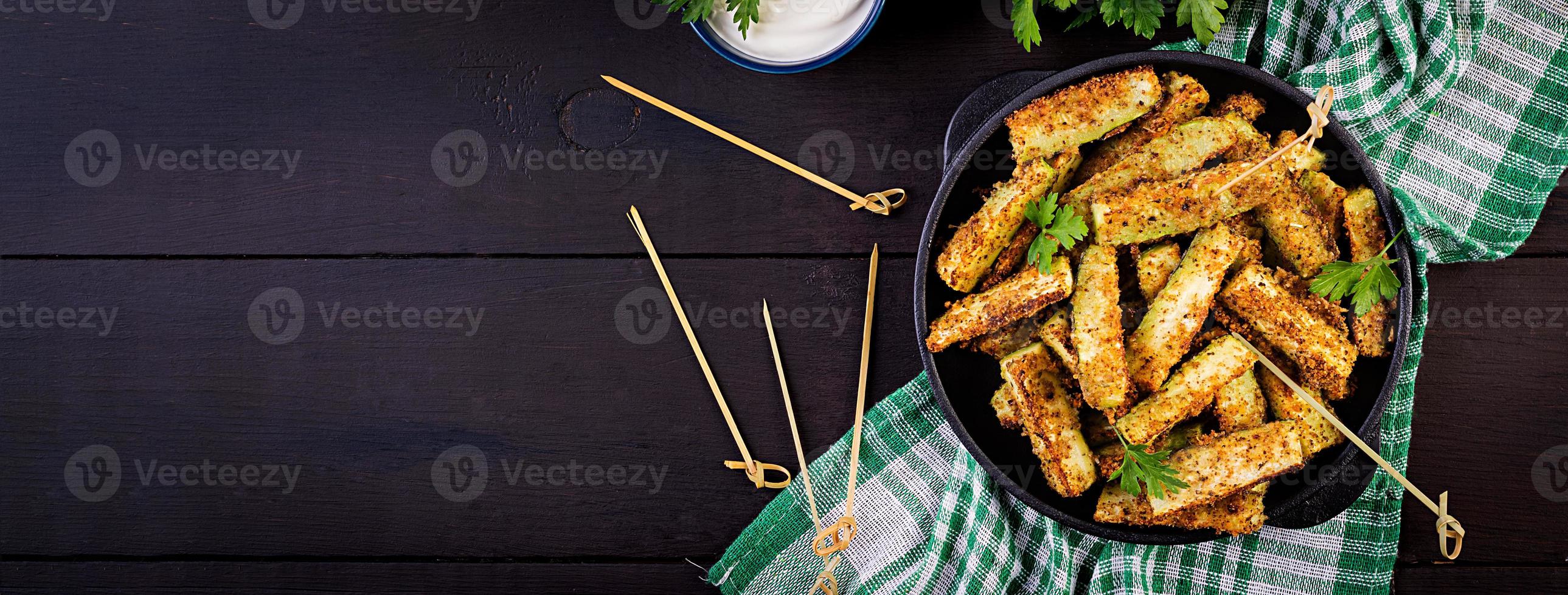 bâtonnets de courgettes cuits au four avec du fromage et de la chapelure. nourriture végétalienne. cuisine végétarienne. bannière. vue de dessus photo