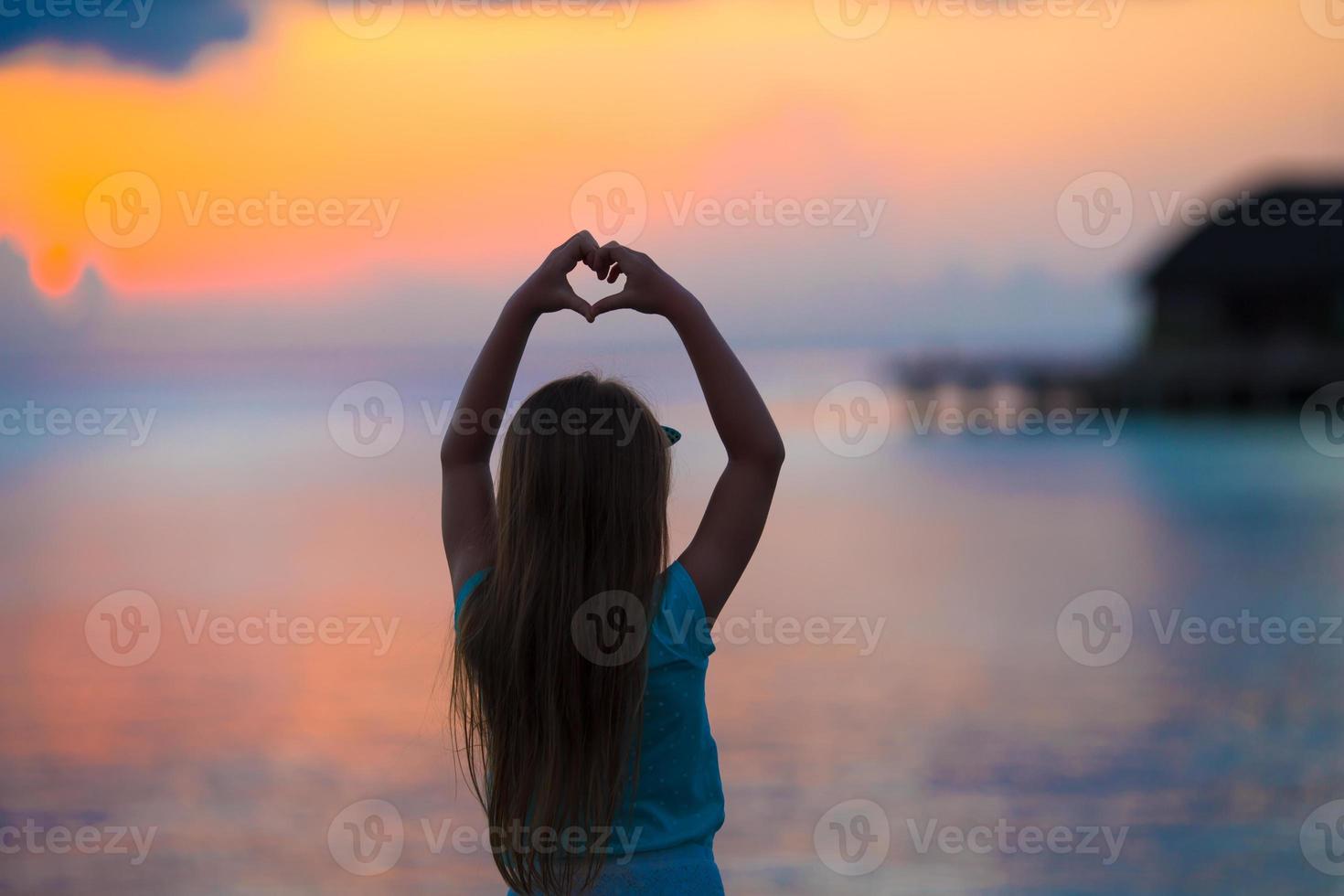 silhouette de coeur faite par les enfants à la main au coucher du soleil photo