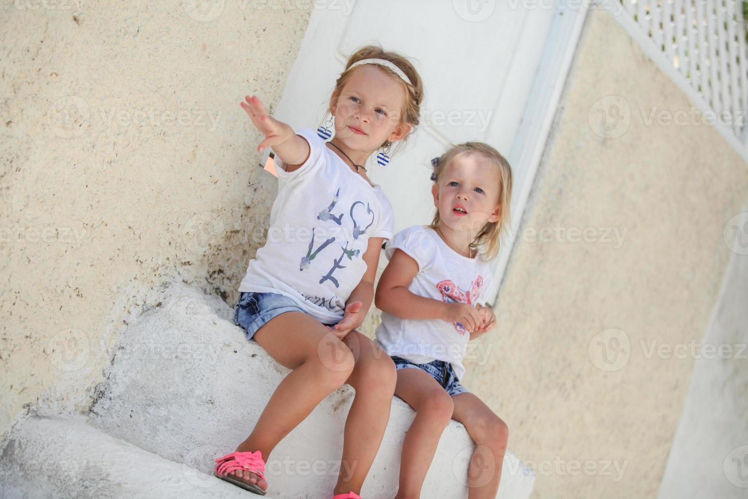 petites soeurs mignonnes assises près de la vieille maison du village grec d'emporio, santorin photo