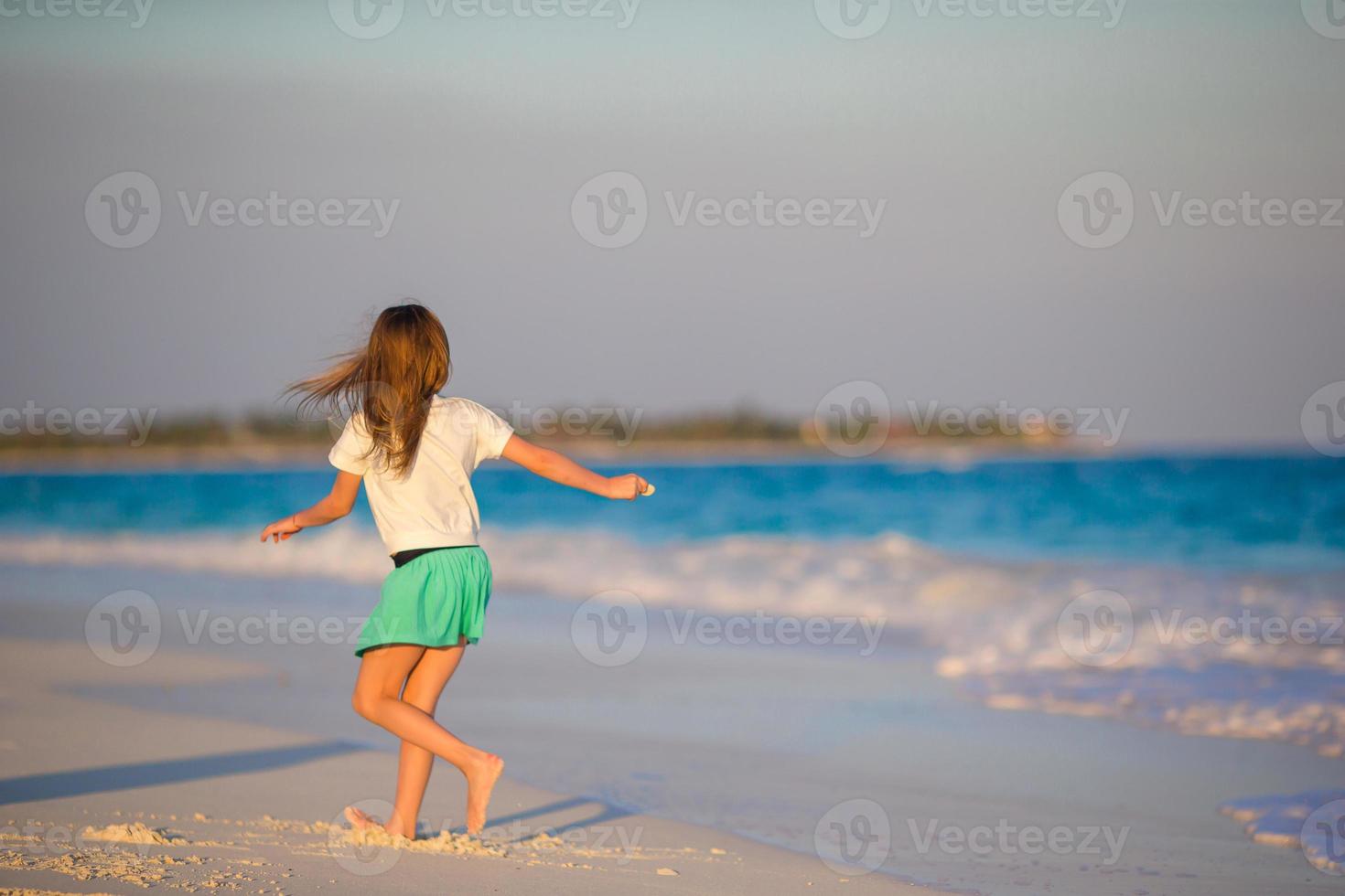 adorable petite fille à la plage s'amusant beaucoup en eau peu profonde photo