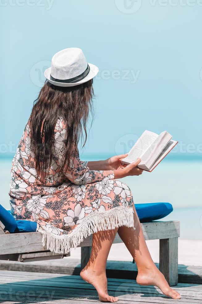 jeune femme lisant un livre pendant la plage maldivienne tropicale photo